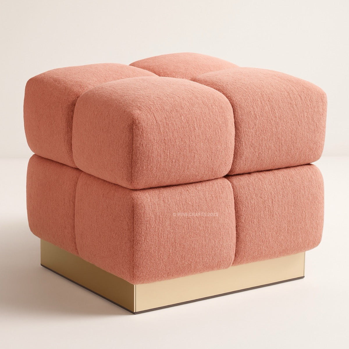 Pink cube-shaped ottoman with a gold base on a beige background