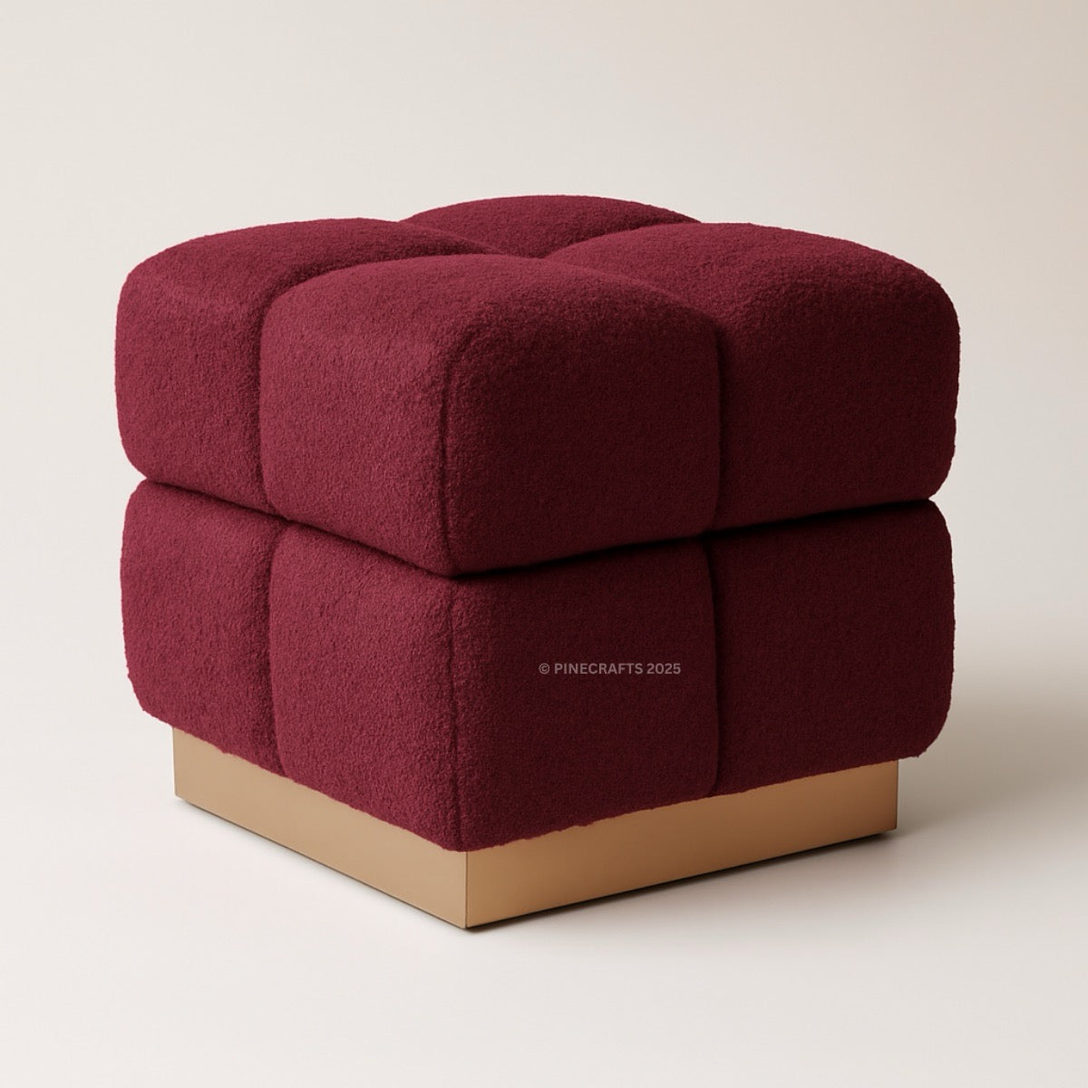 Maroon cube-shaped ottoman with a wooden base on a beige background