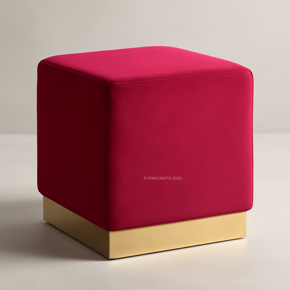 Red cube-shaped ottoman with a gold base on a neutral background