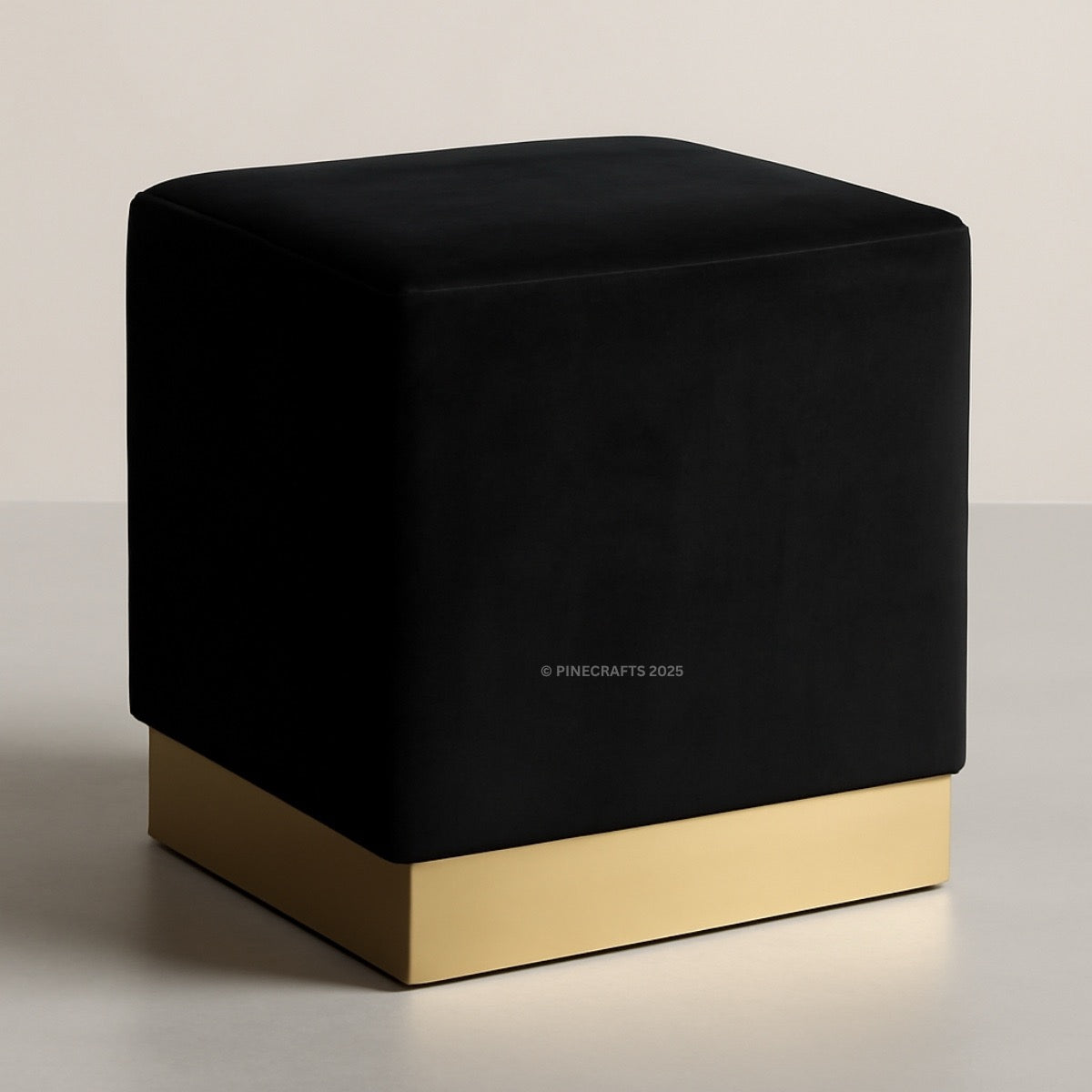 Black cube-shaped ottoman with a gold base on a neutral background