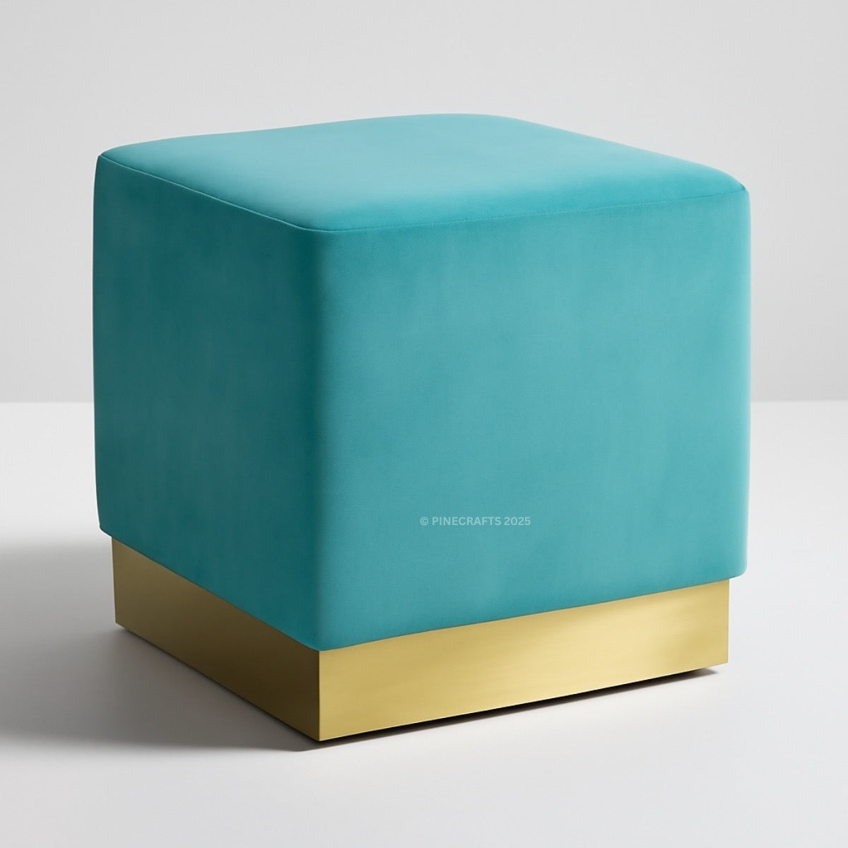 Teal cube-shaped ottoman with a gold base on a light gray background