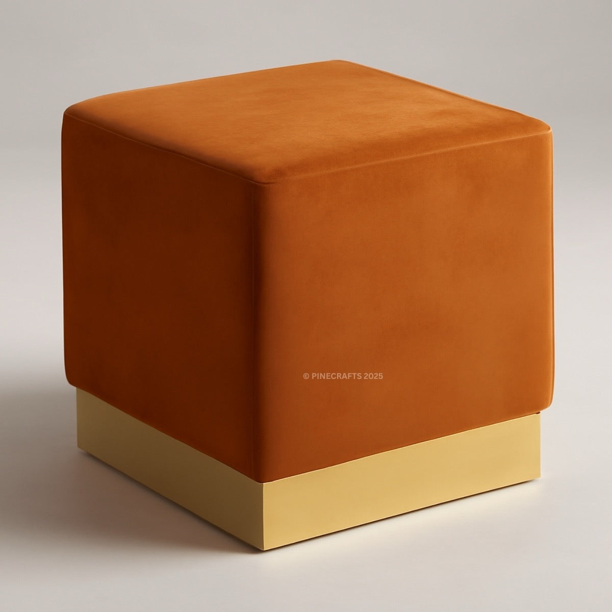 Orange cube-shaped ottoman with a gold base on a neutral background