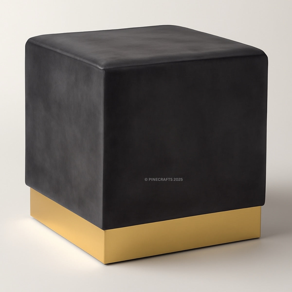 Black cube-shaped ottoman with a gold base on a light gray background