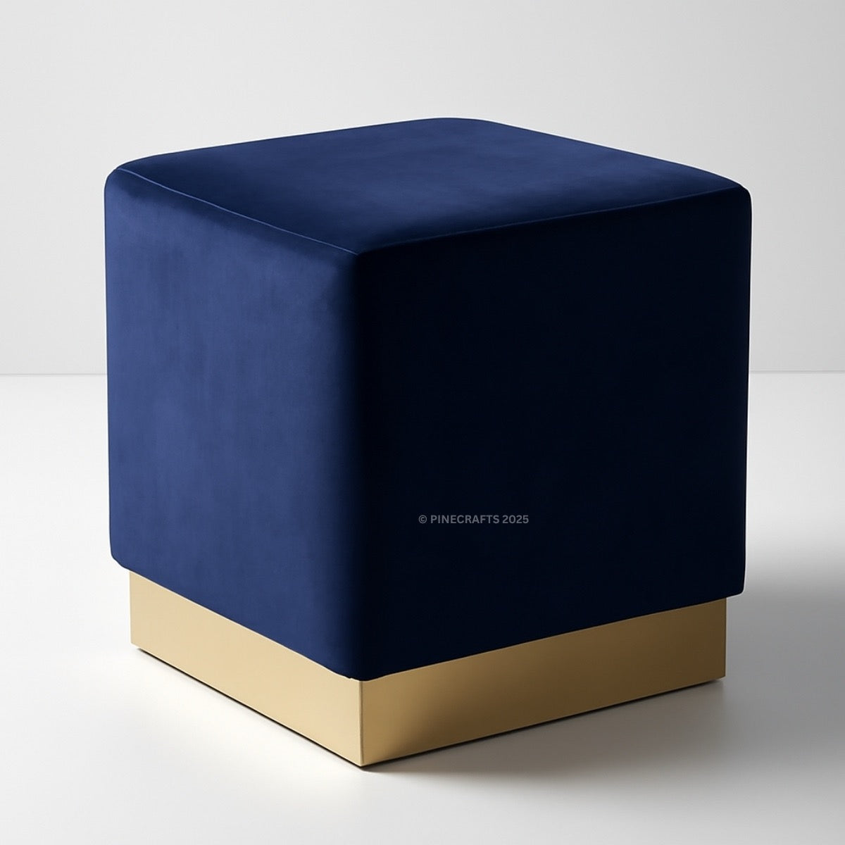 Blue cube-shaped ottoman with a gold base on a white background