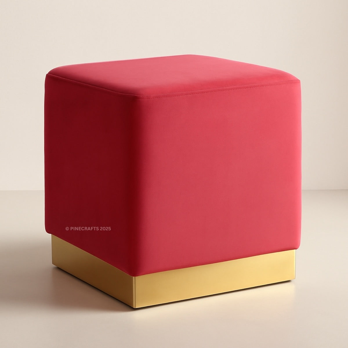 Red cube-shaped ottoman with a gold base on a beige background