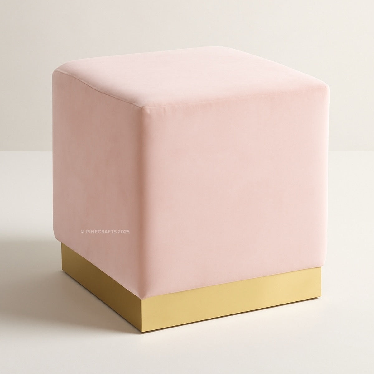 Pink cube-shaped ottoman with a gold base on a light beige background