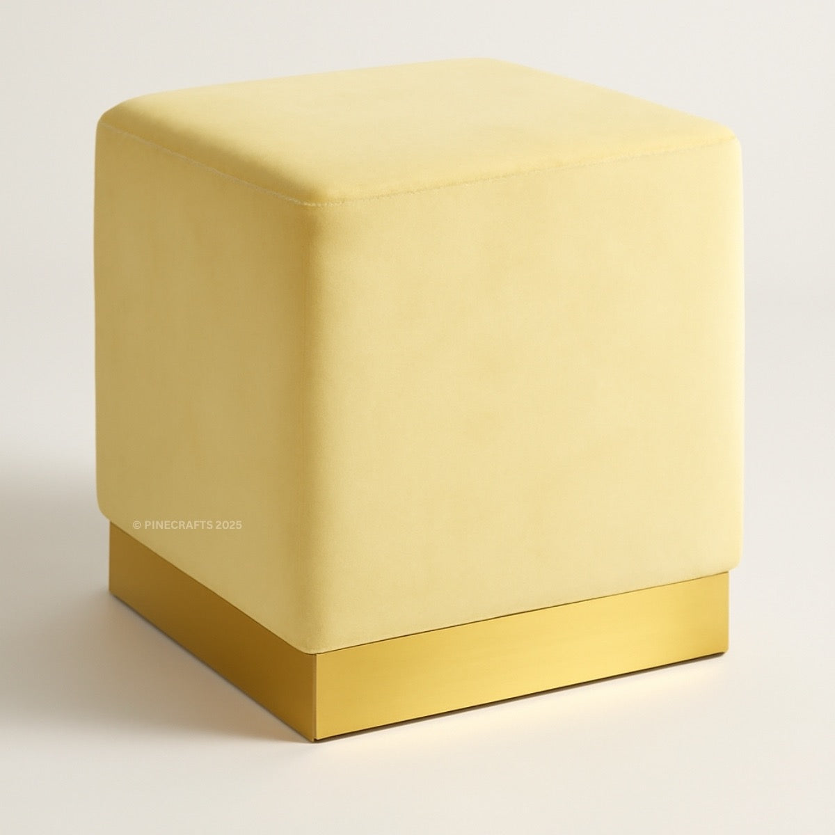 Beige cube-shaped ottoman with gold base on a light gray background
