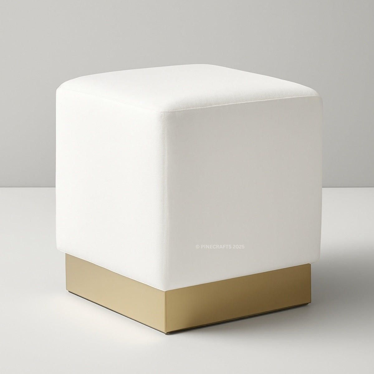 White cube-shaped ottoman with a gold base on a gray background