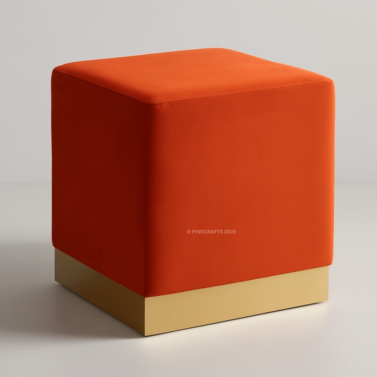 Orange cube-shaped ottoman with a gold base on a light gray background