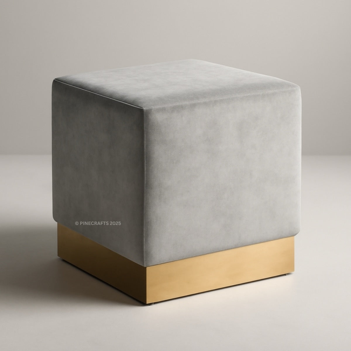 Gray cube-shaped ottoman with a gold base on a neutral background