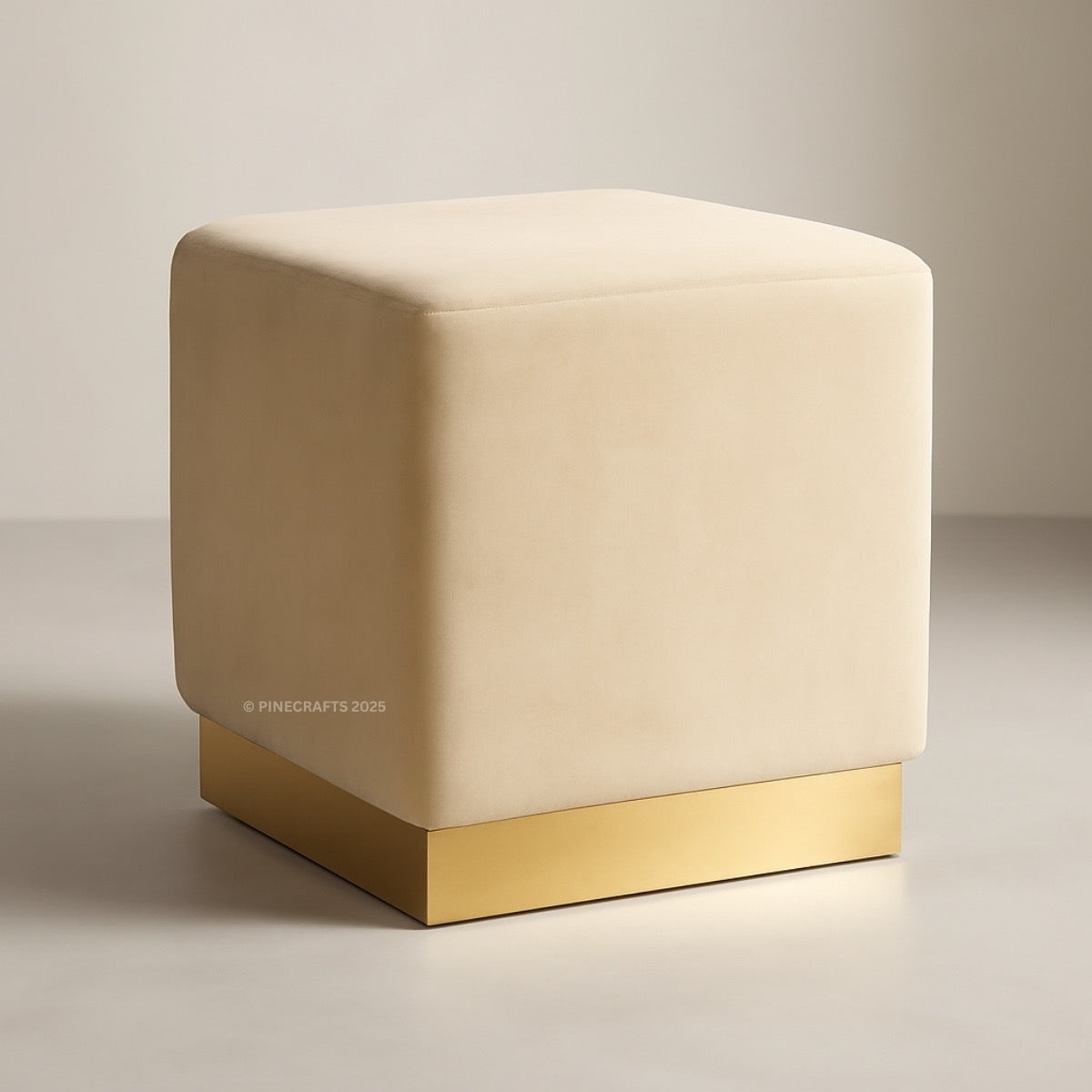 Beige cube-shaped ottoman with a gold base on a neutral background