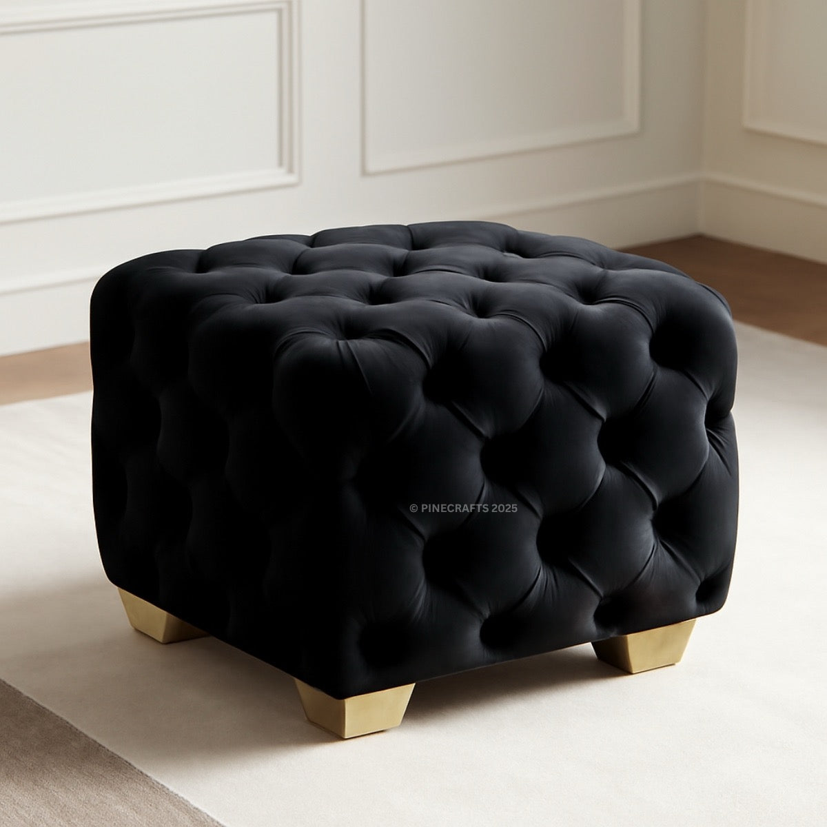 Black tufted ottoman with gold legs on a white rug