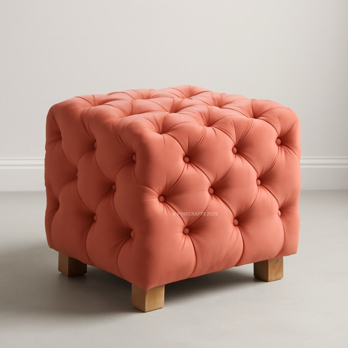 Coral tufted ottoman with wooden legs on a neutral background