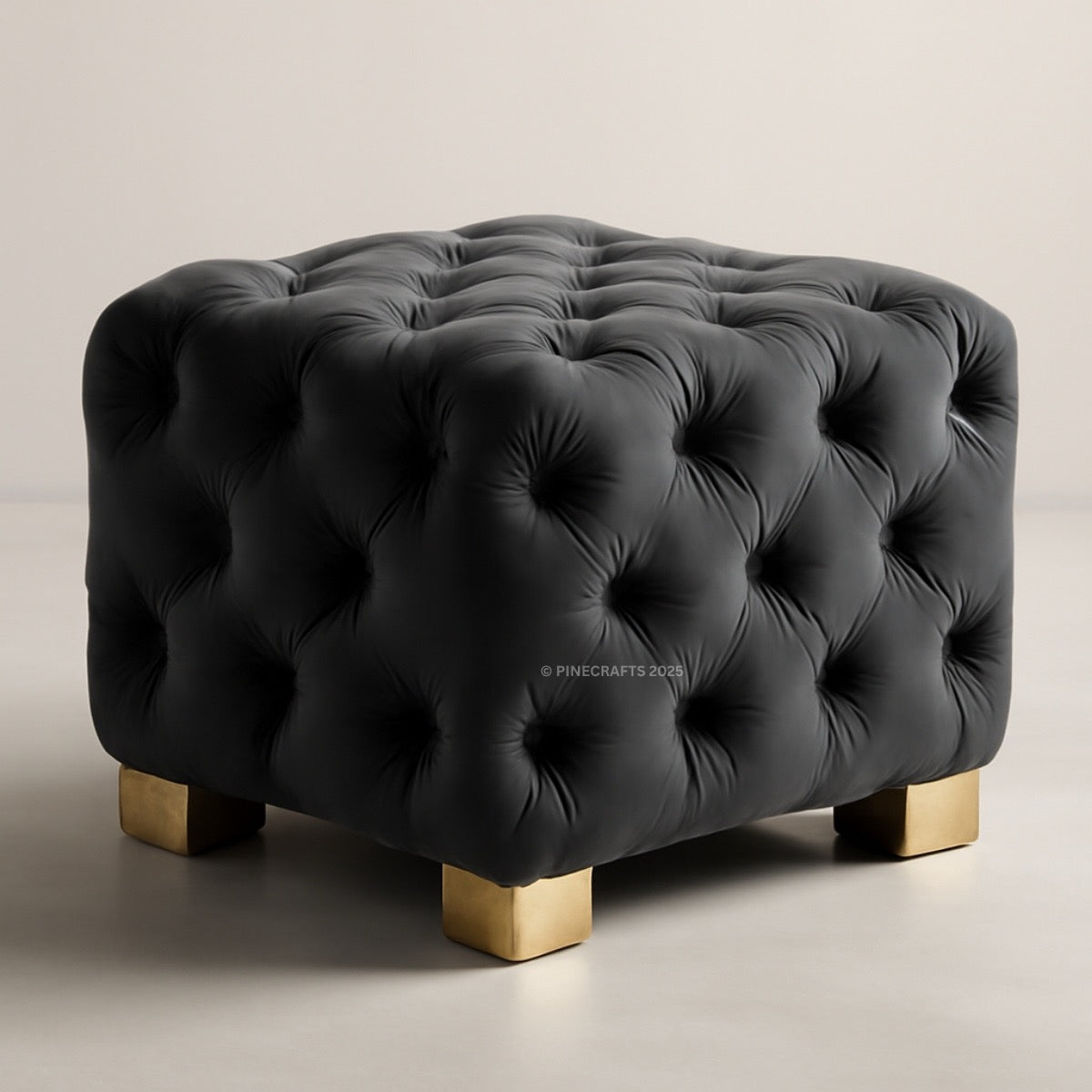 Black tufted ottoman with gold legs on a neutral background