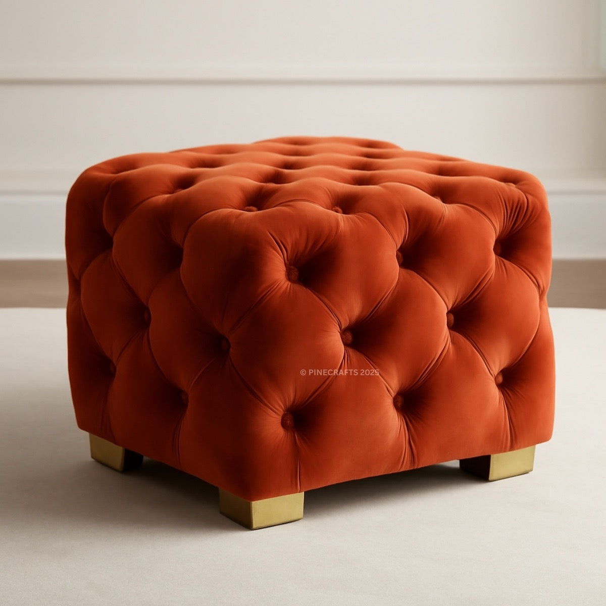 Orange tufted ottoman with gold legs on a neutral background