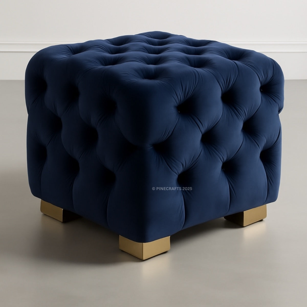 Blue tufted ottoman with gold legs on a neutral background