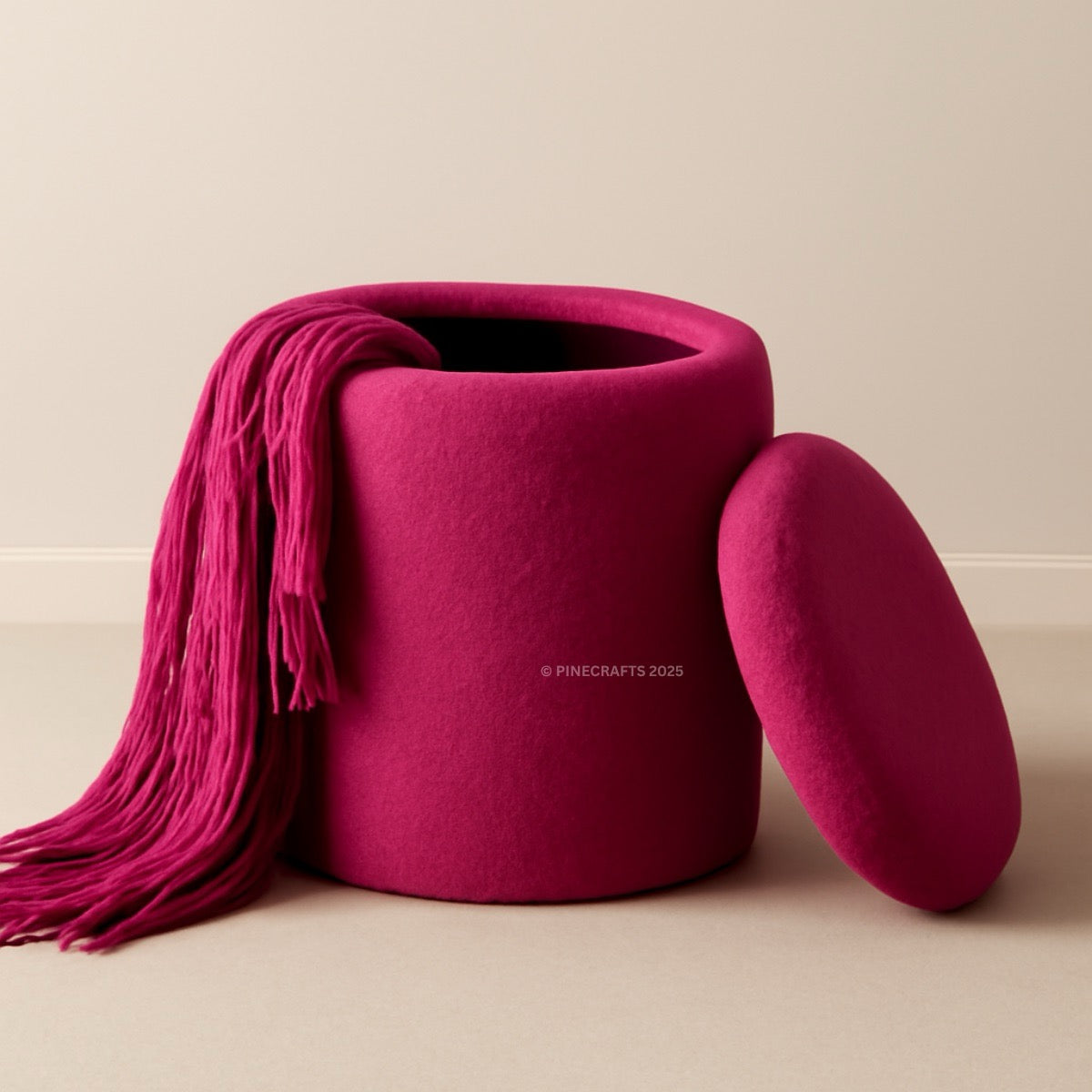 Pink ottoman with a matching pink blanket draped over it on a beige background