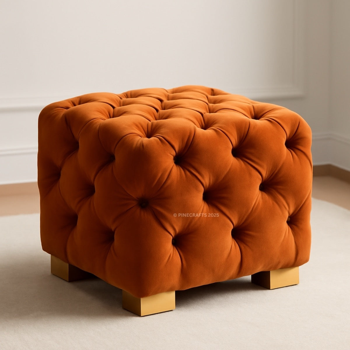 Orange tufted ottoman with gold legs on a neutral background
