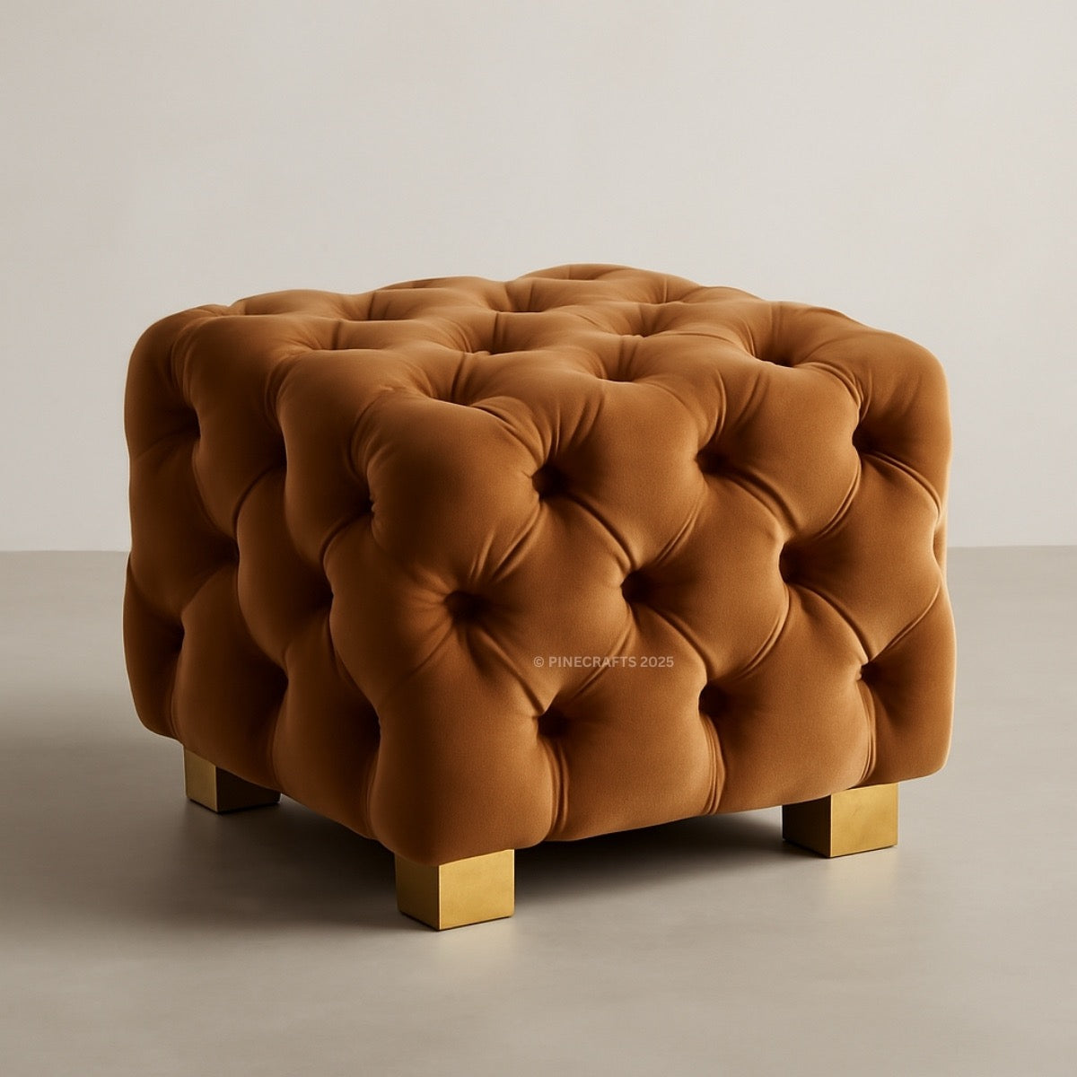 Brown tufted ottoman with gold legs on a neutral background