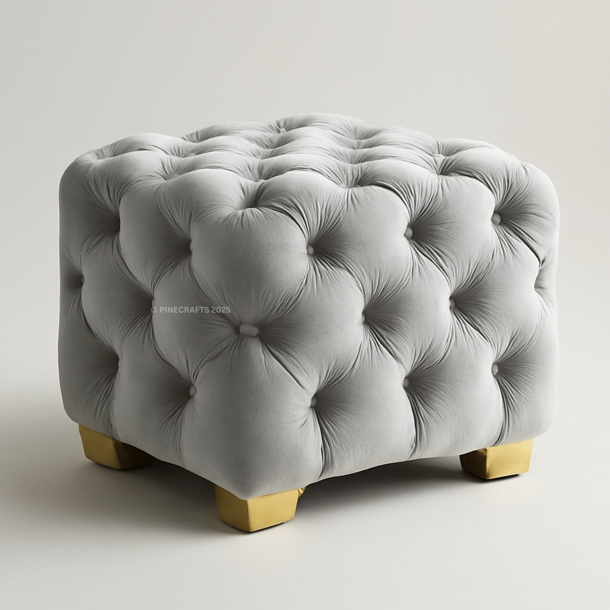 Gray tufted ottoman with gold legs on a light gray background