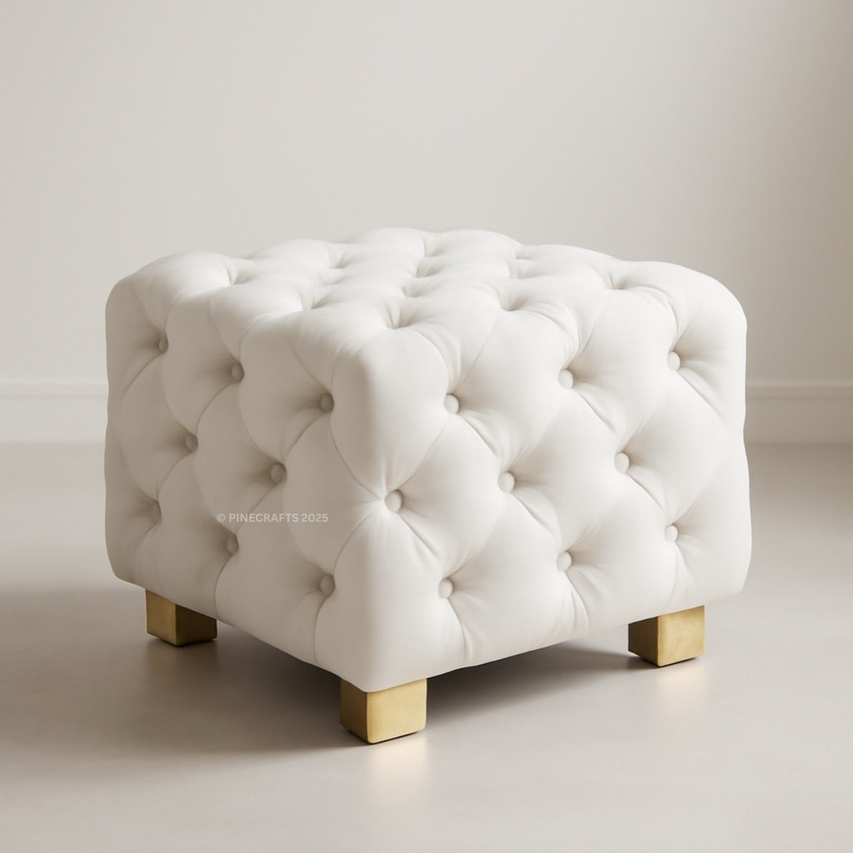 White tufted ottoman with gold legs on a neutral background