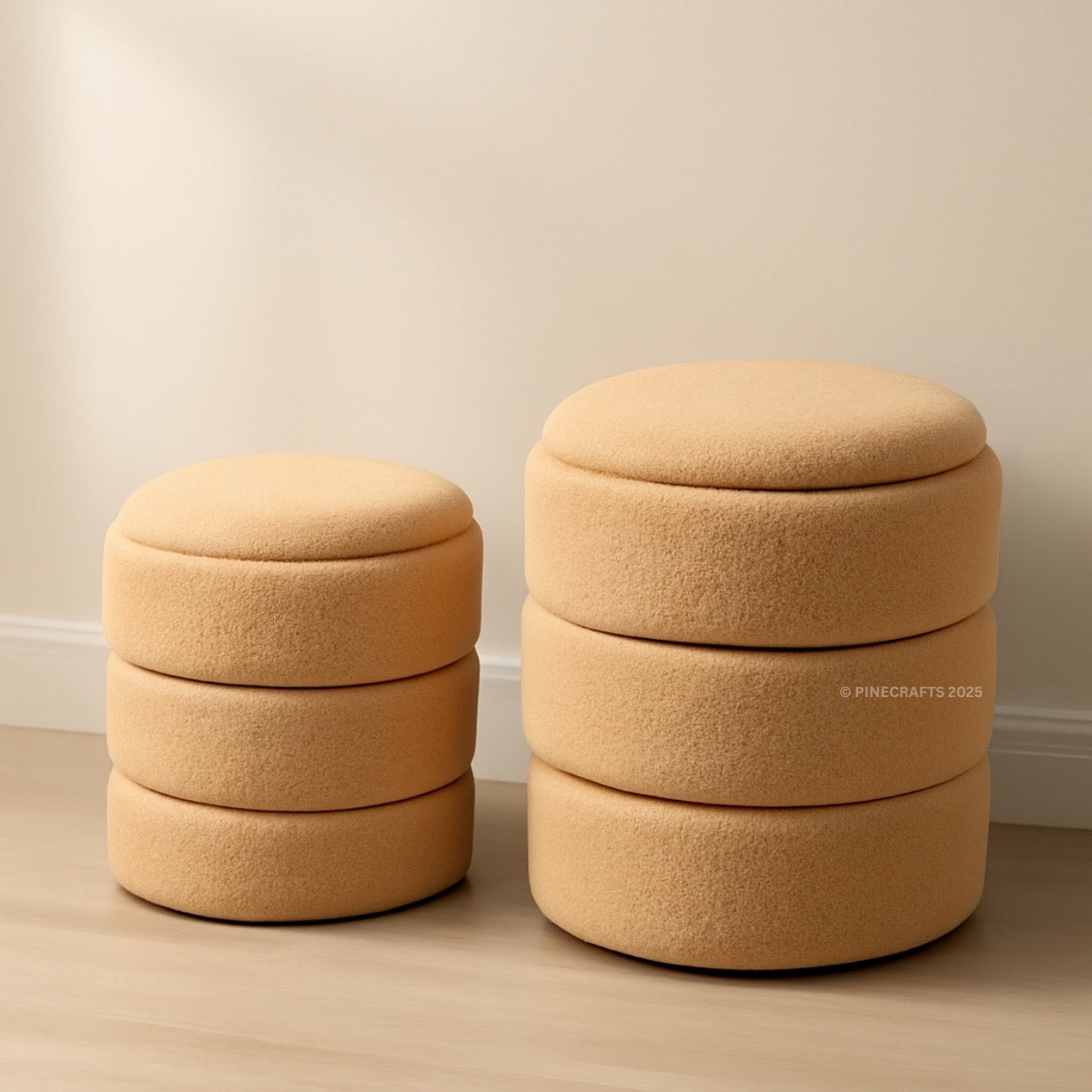 Two beige ottomans stacked on a wooden floor with a plain wall background