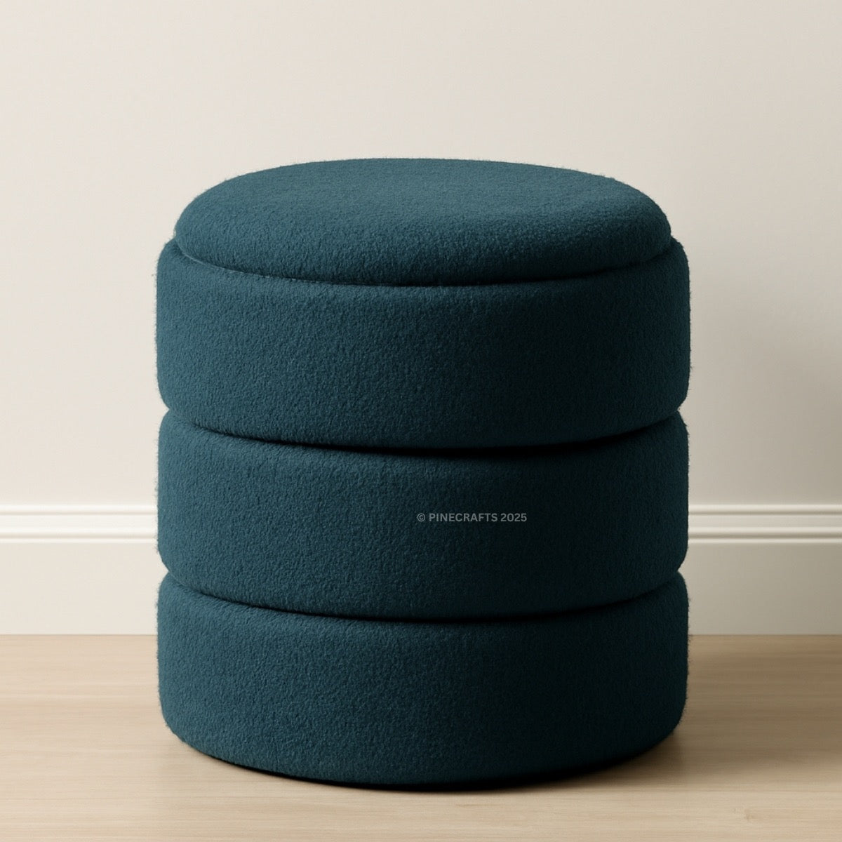 Stack of three teal ottomans on a wooden floor with a neutral wall background