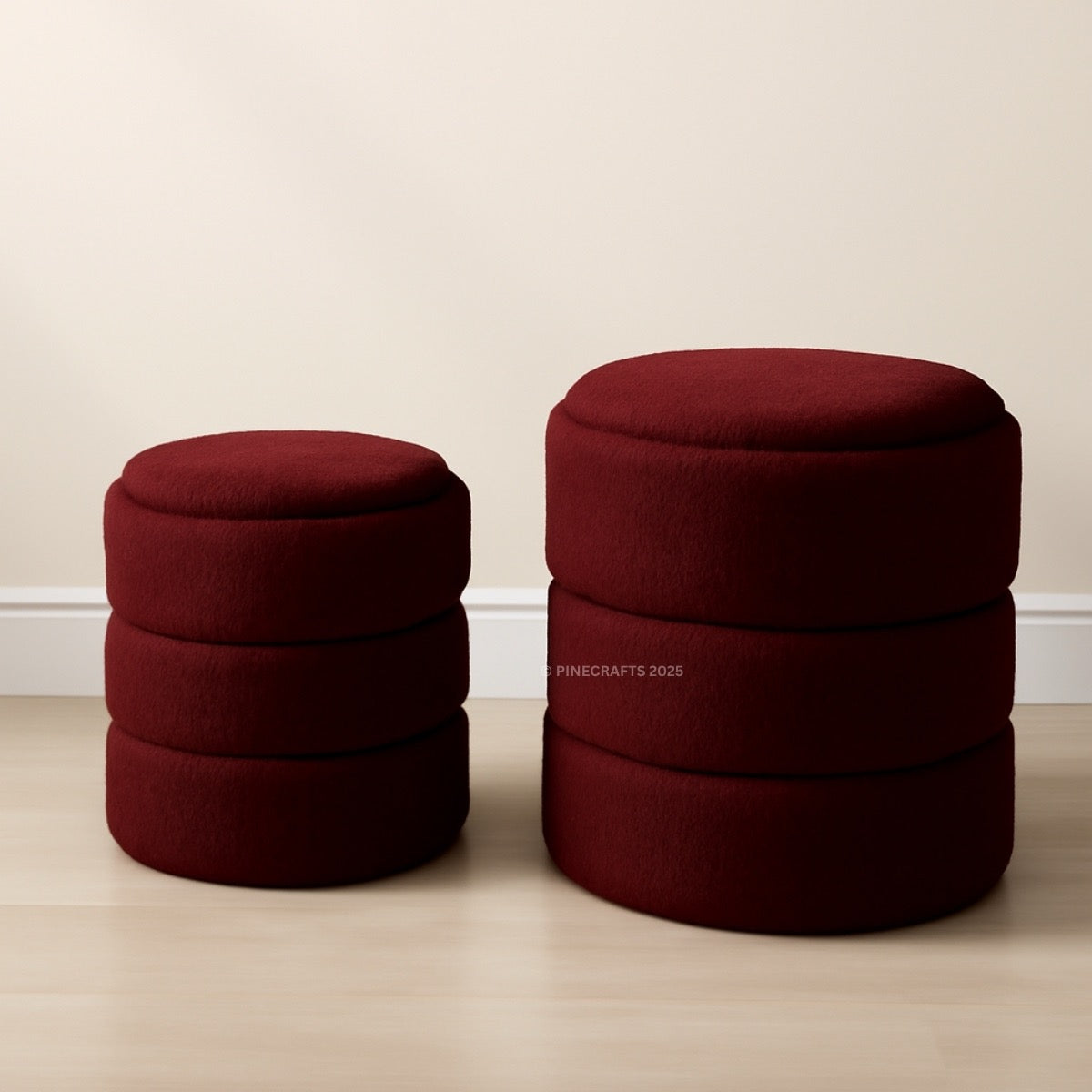 Two red cylindrical stools on a wooden floor with a plain wall background.