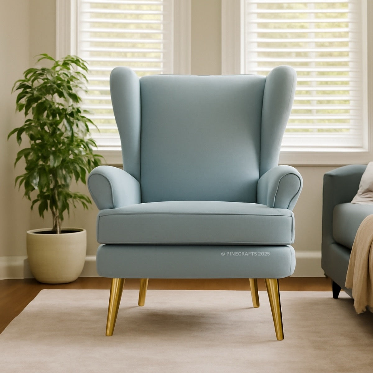 Light blue armchair with gold legs in a room with a plant and window blinds.