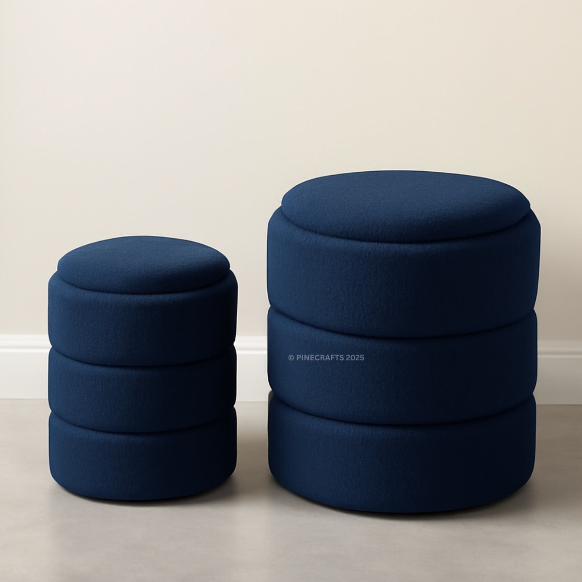 Two navy blue ottomans stacked on a light gray floor with a white wall background.