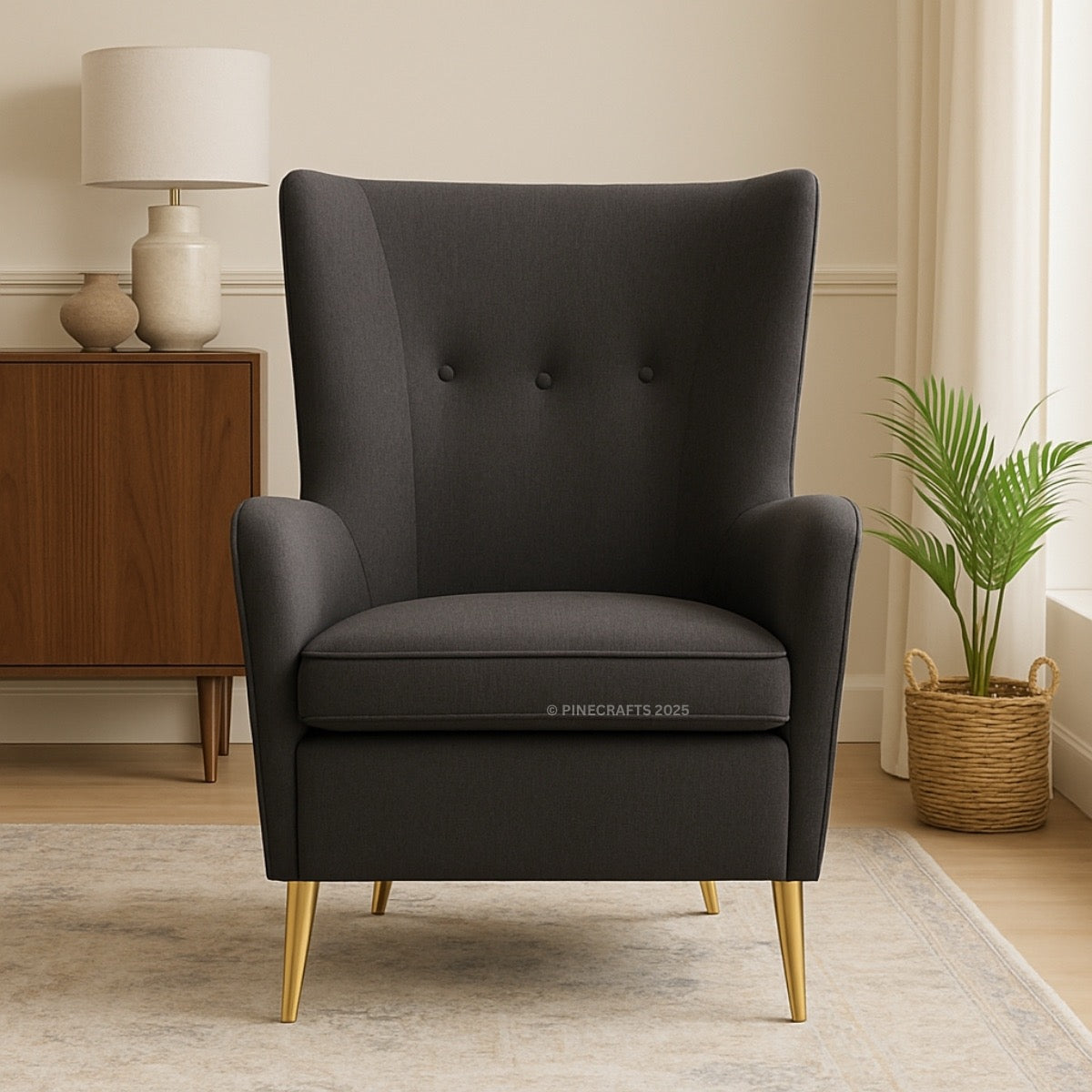 Dark gray armchair with gold legs in a room with a wooden cabinet and lamp.