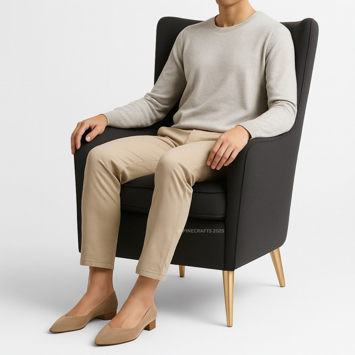Person sitting on a black chair wearing a beige sweater and pants with tan shoes.