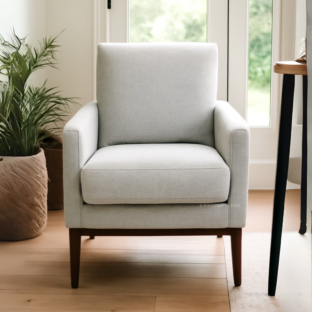 Gray armchair in a room with a plant and a table