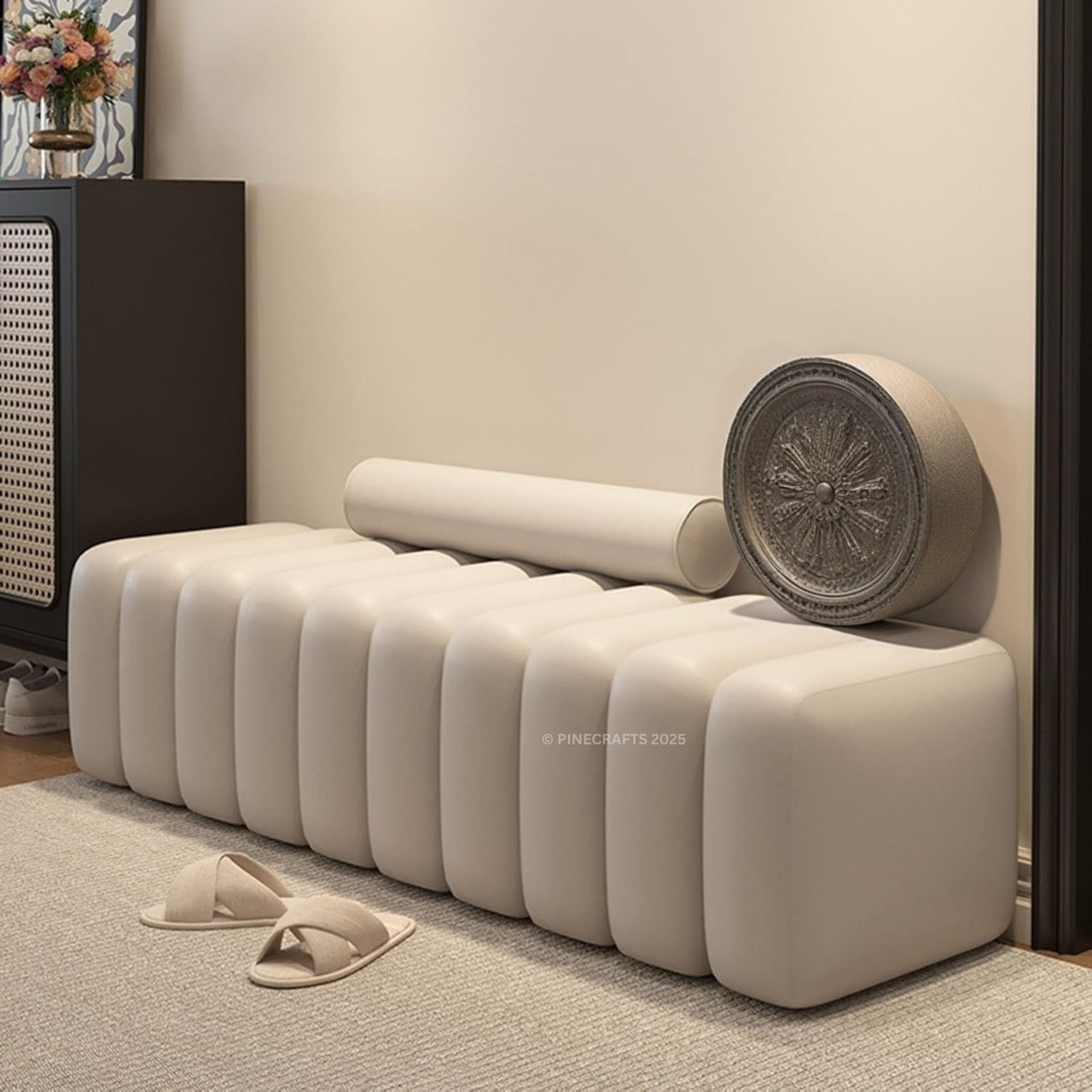 Beige ottoman with a decorative wheel on top in a room setting.