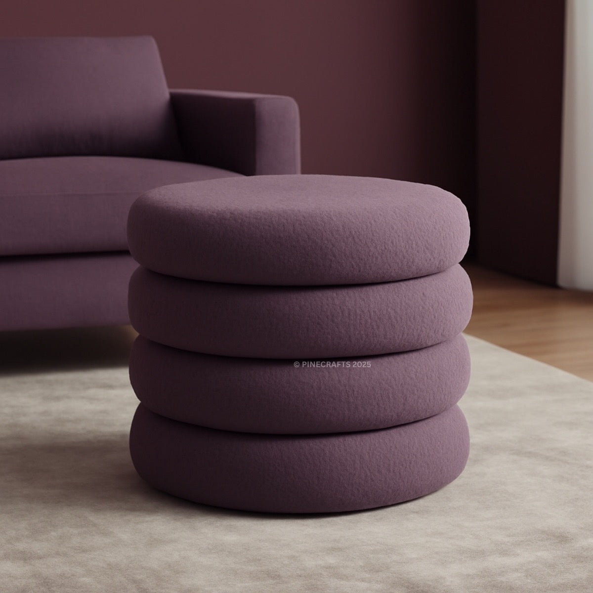 Stack of purple cushions on a light gray rug with a blurred purple sofa in the background.