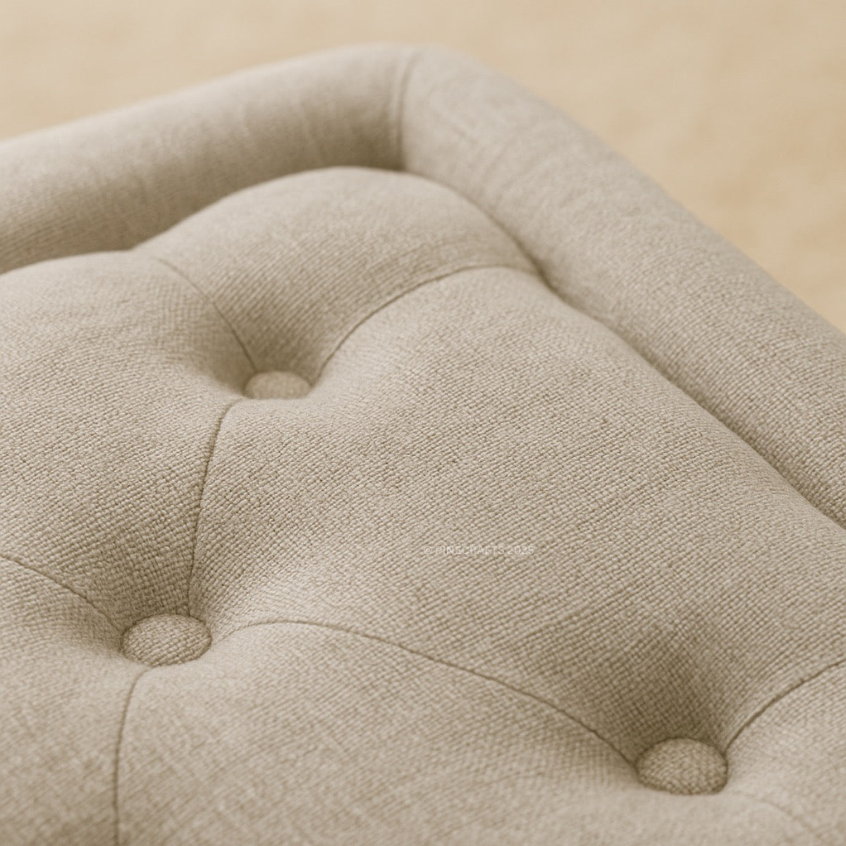 Close-up of a beige upholstered chair with tufted button details on a beige background