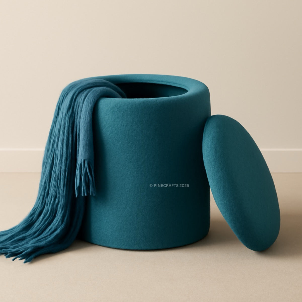 Teal ottoman with a matching blanket on a beige background