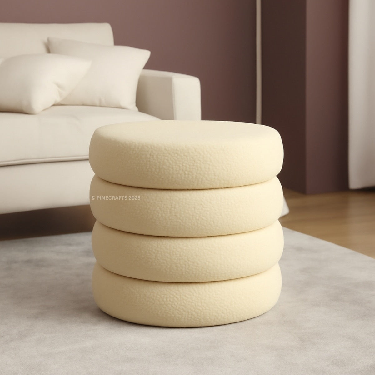 Stack of beige textured cushions on a light gray rug with a blurred sofa in the background.