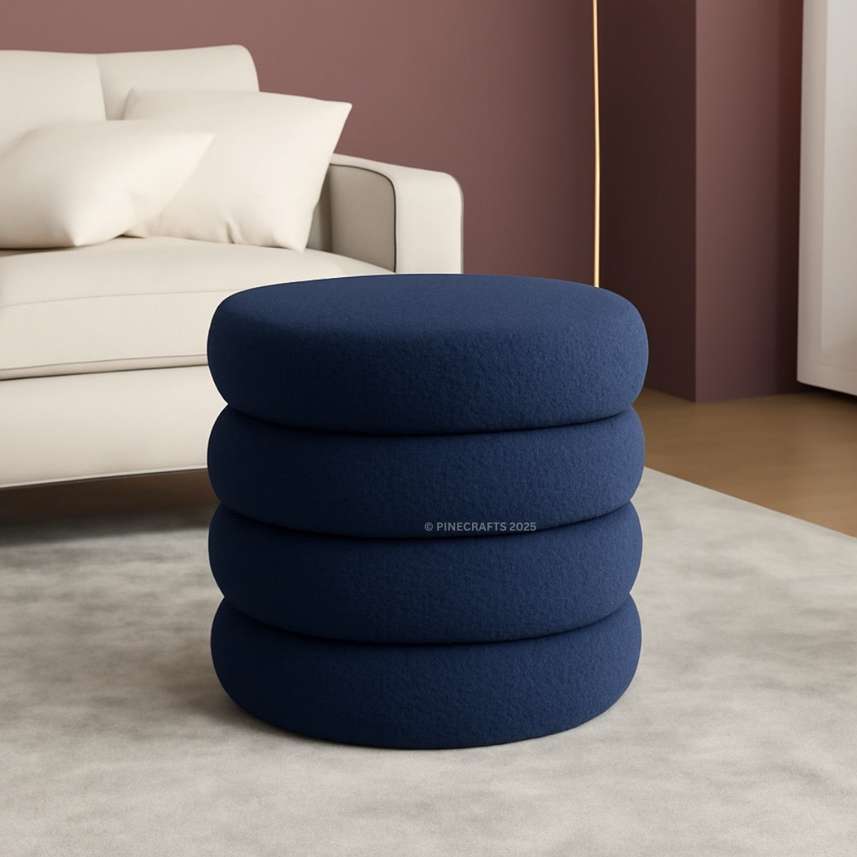 Stack of blue cushions on a light gray rug with a beige sofa in the background.