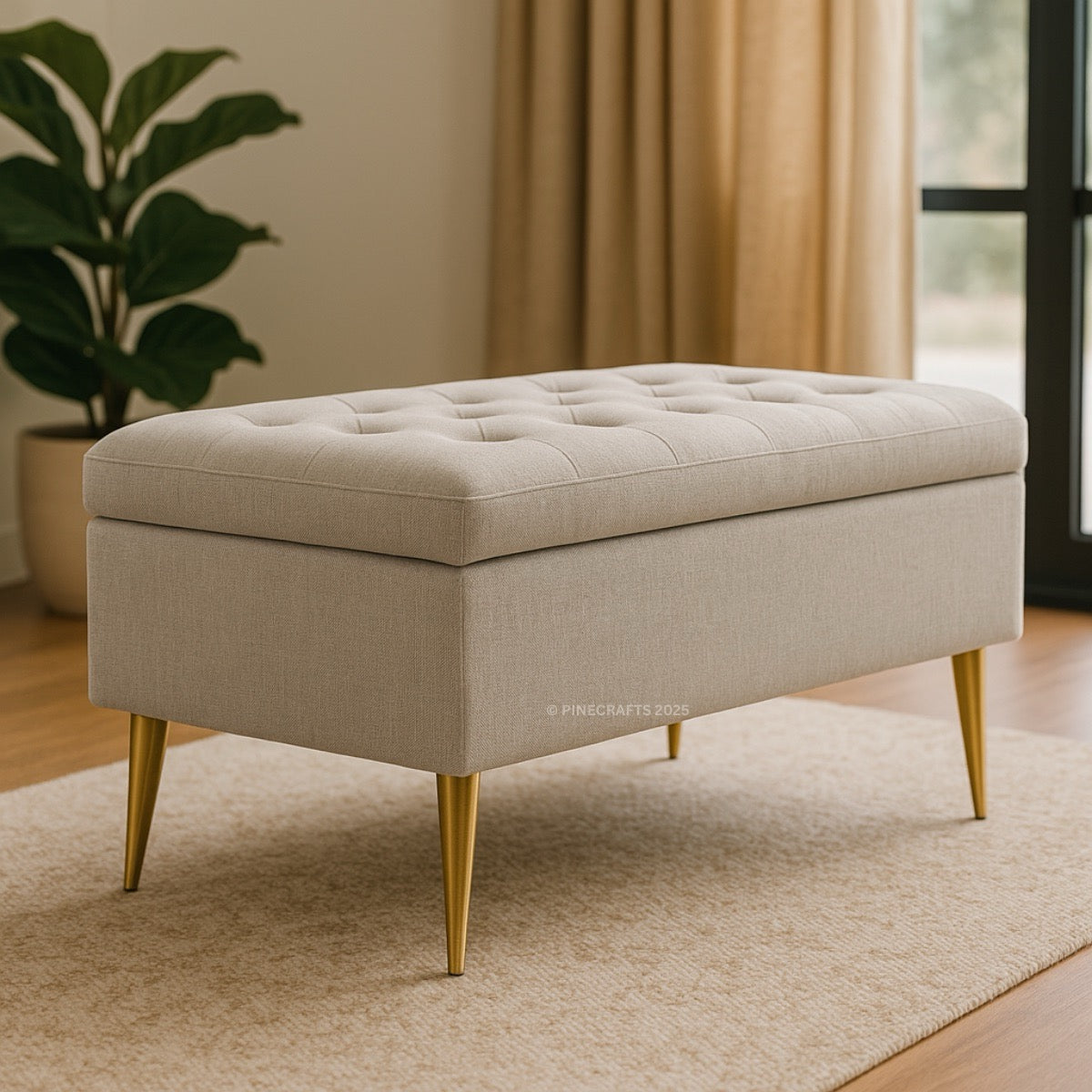 Beige tufted ottoman with gold legs on a beige rug, plant and curtain in the background