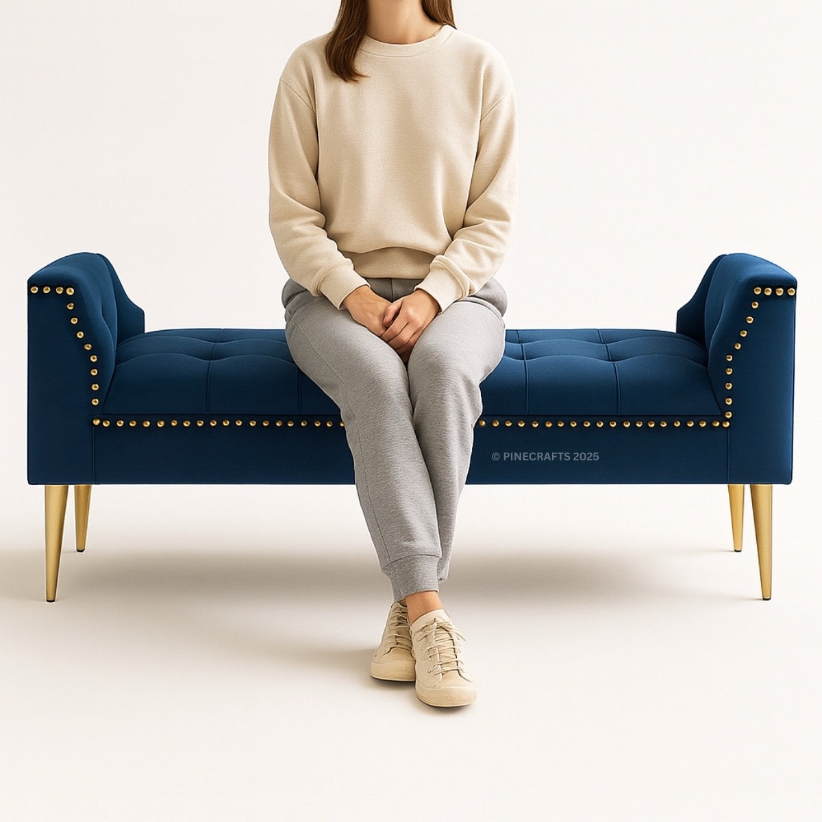 Person sitting on a blue bench with gold nailhead trim against a white background