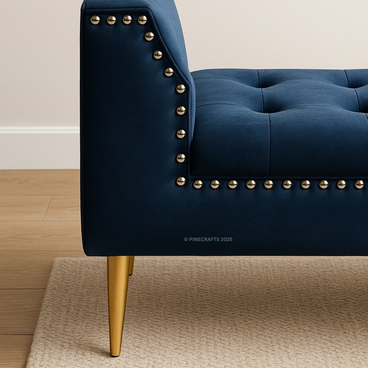 Blue upholstered chair with gold nailhead trim and legs on a beige carpet.
