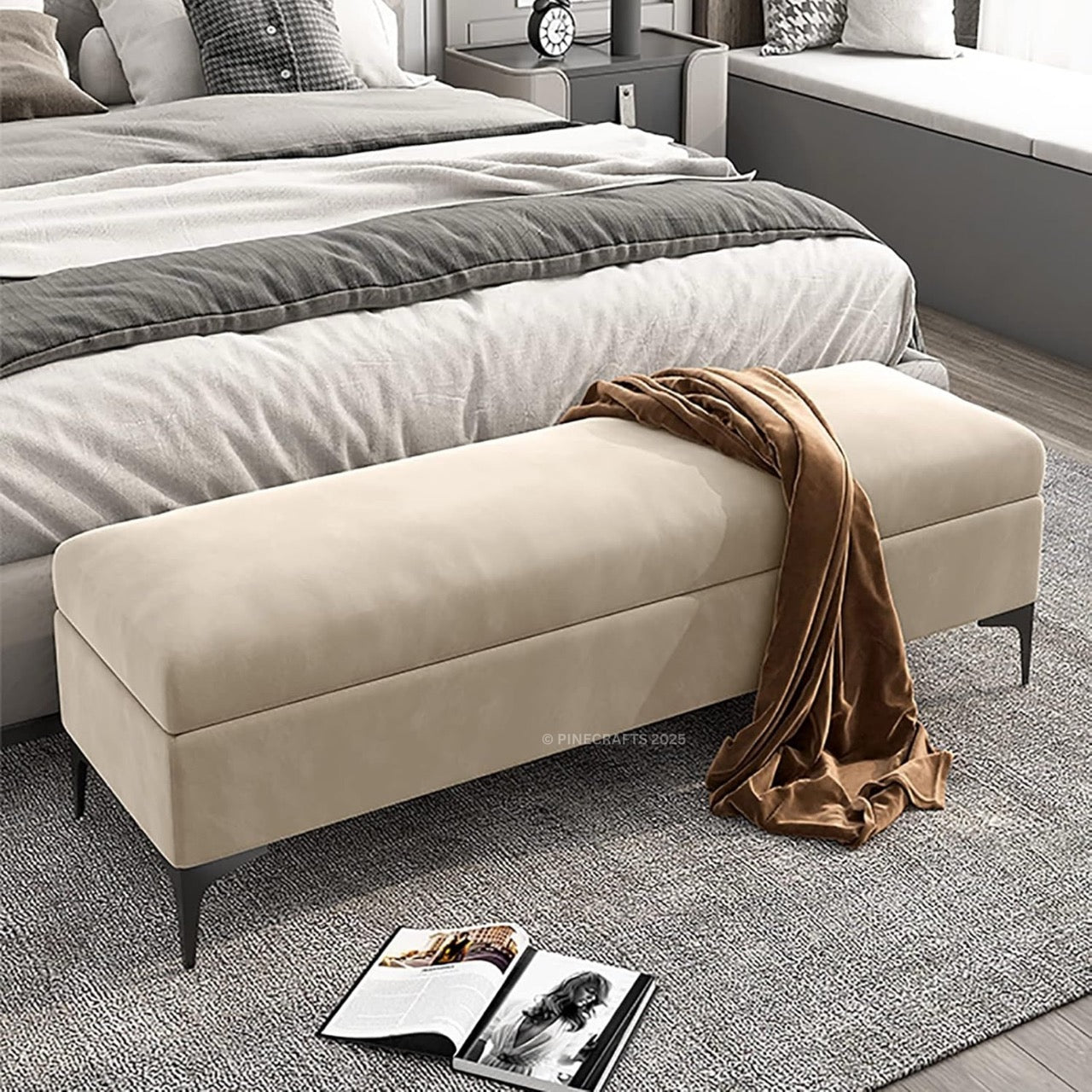 Beige ottoman with a brown blanket in a bedroom setting.