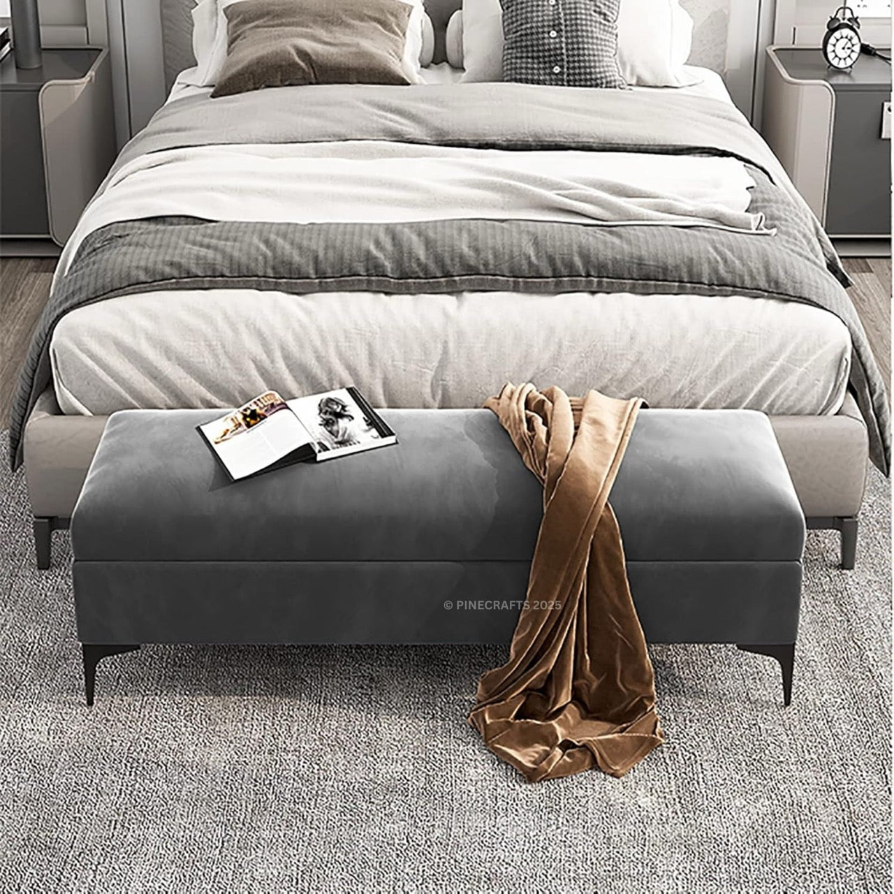 Gray upholstered bench with a brown blanket draped over it in front of a bed.