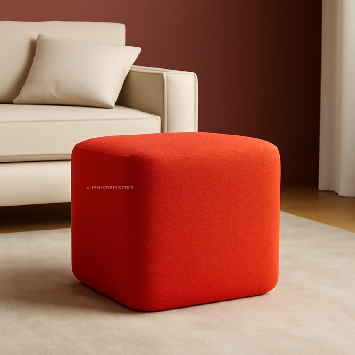 Red cube-shaped ottoman in a living room setting with a beige sofa.