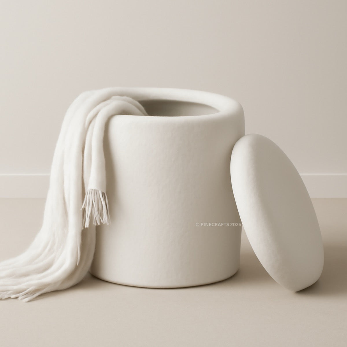 White ceramic jar with a matching lid and white scarf on a beige background