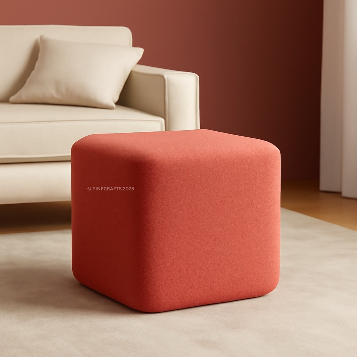 Red cube-shaped ottoman in a living room setting with a beige sofa.