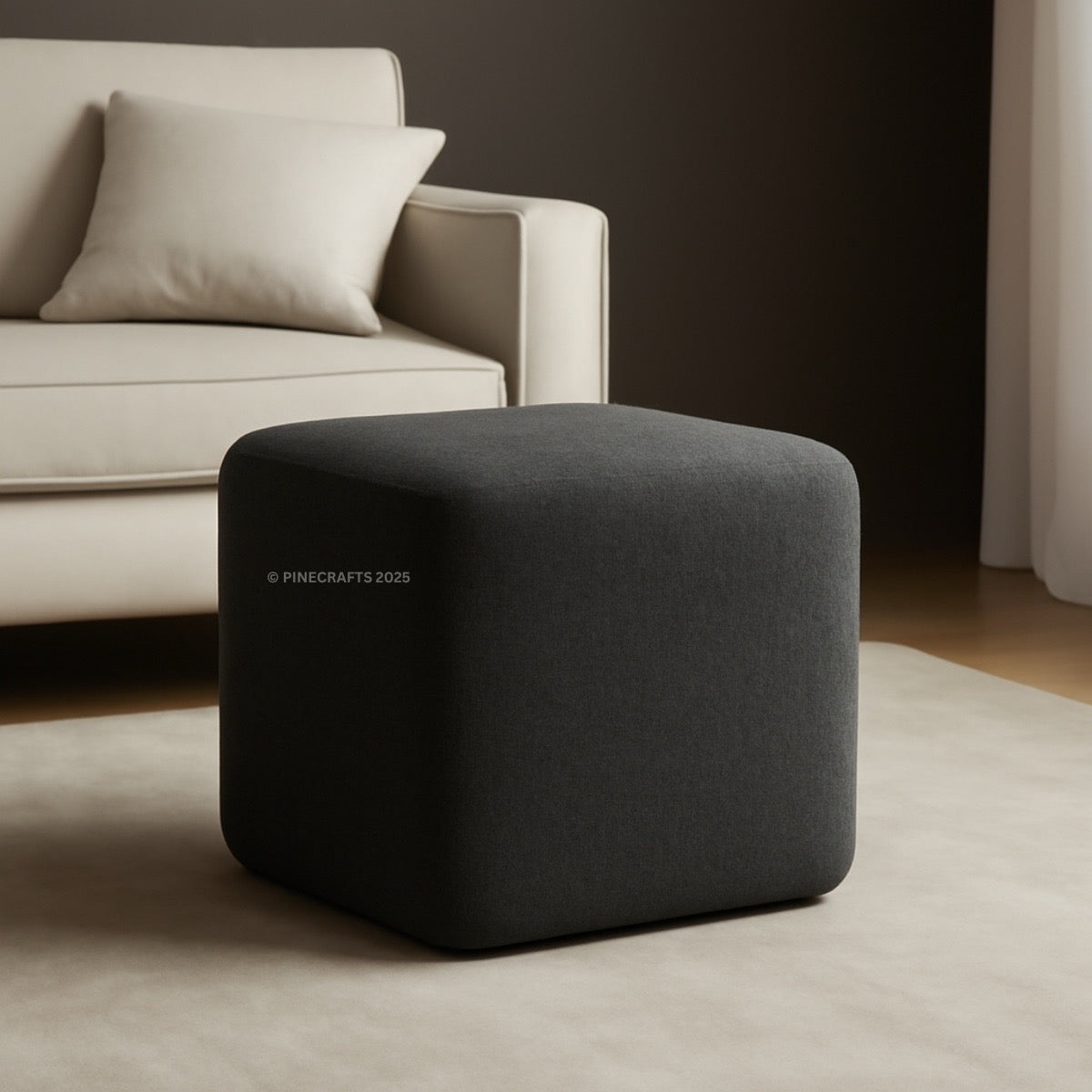 Gray cube-shaped ottoman in a living room setting with a beige sofa.