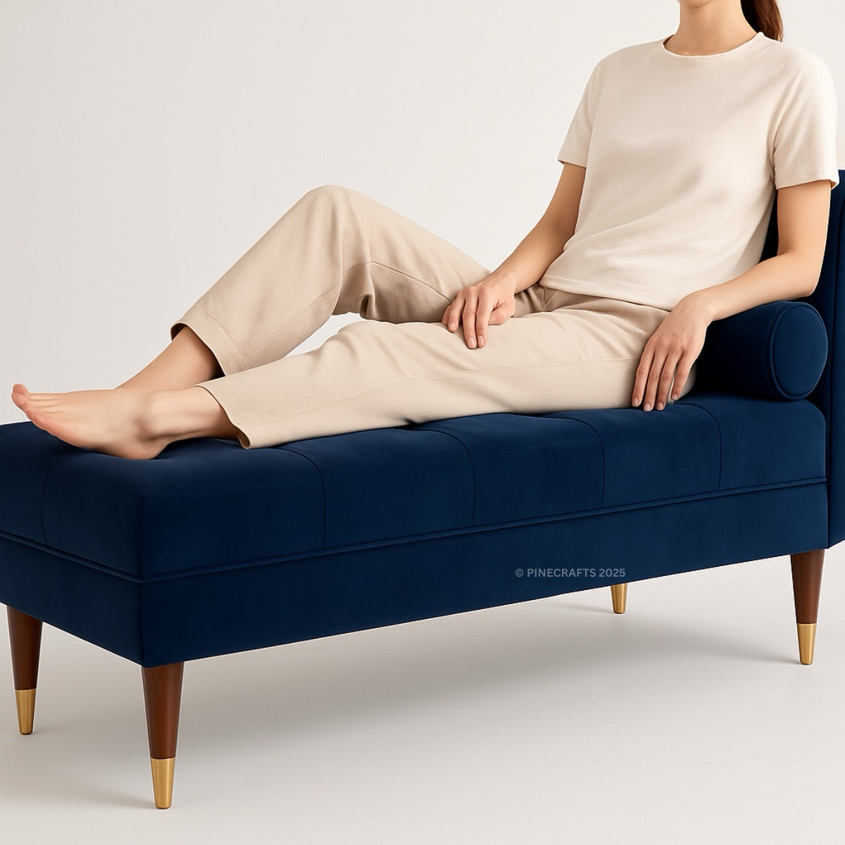 Person sitting on a navy blue bench with gold legs against a plain background