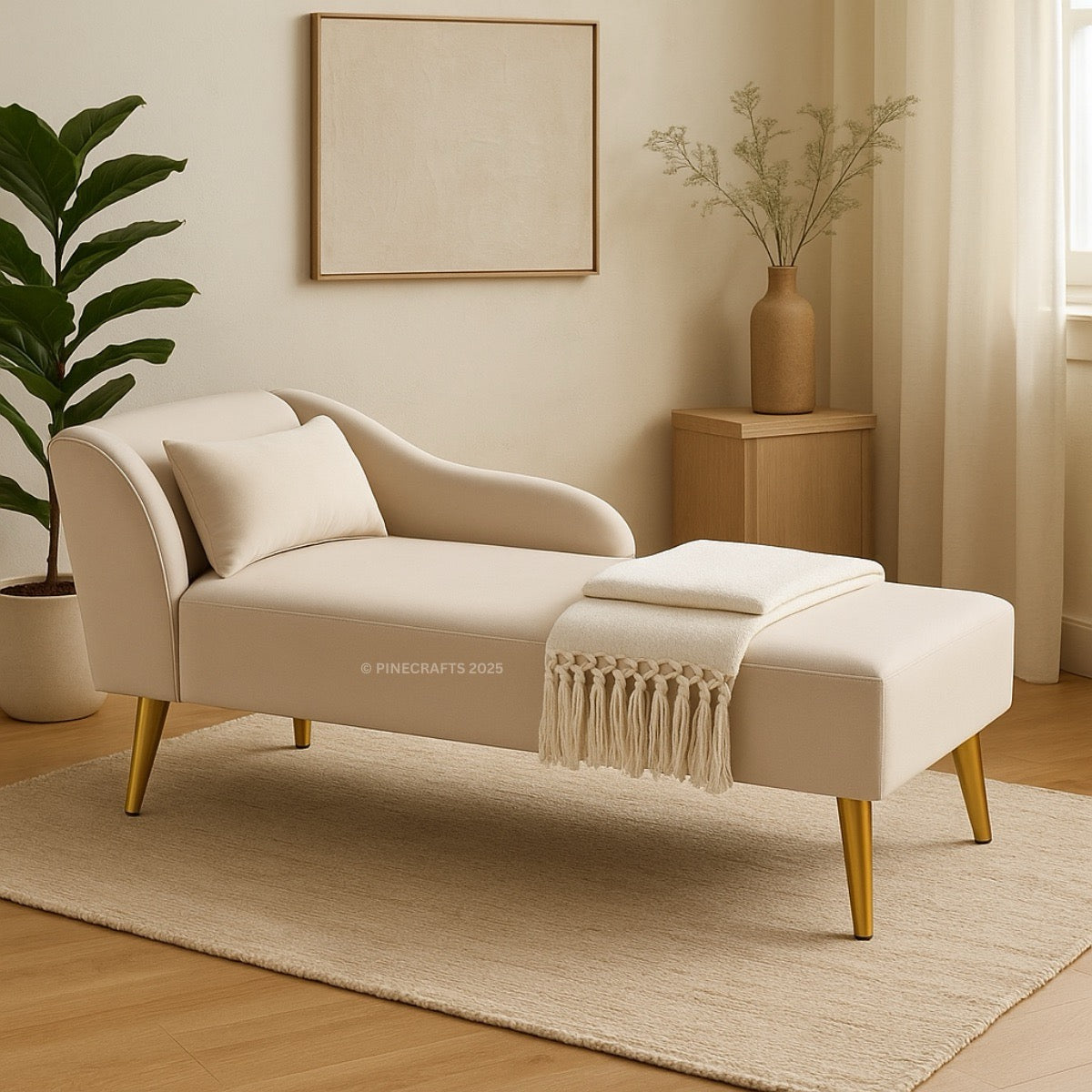 Beige chaise lounge with gold legs in a room with a plant and wooden cabinet.